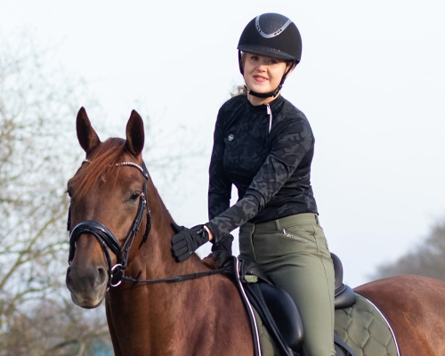 Rękawiczki jeździeckie zimowe QHP Vienna w kolorze czarnym zaprezentowane przez modelkę podczas jazdy konnej