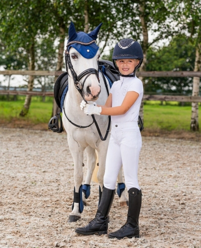 Białe bryczesy dziecięce QHP Junior Fera zaprezentowane przez modelkę