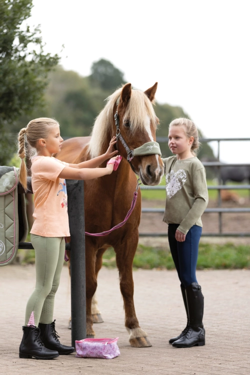 Bawełniana bluzka jeździecka dla dziewczynki HKM Horse Spirit zaprezentowana przez modelkę podczas zabawy z kucykiem