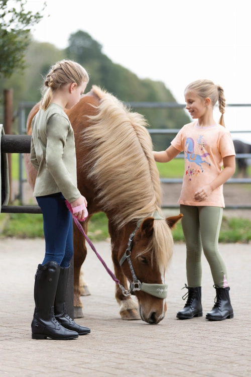 Bawełniana bluzka jeździecka dla dziewczynki HKM Horse Spirit zaprezentowana przez modelkę podczas zabawy z kucykiem