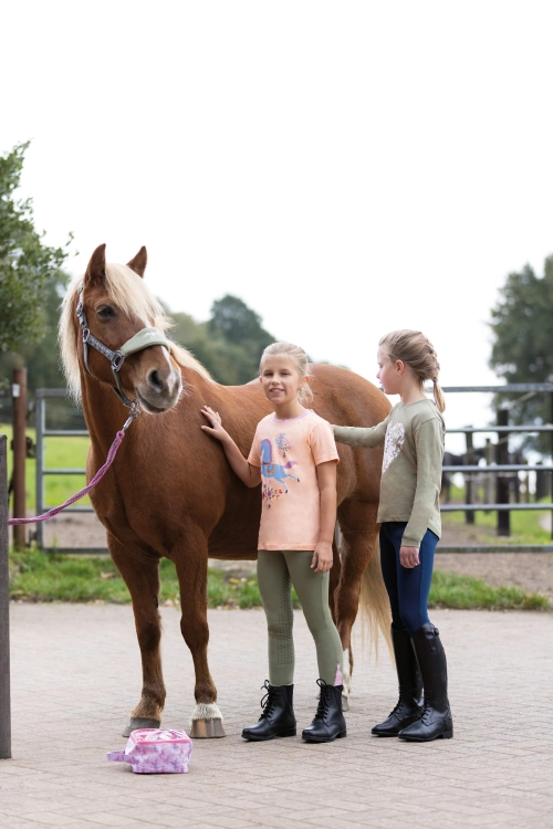 Bawełniana bluzka jeździecka dla dziewczynki HKM Horse Spirit zaprezentowana przez modelkę podczas zabawy z kucykiem