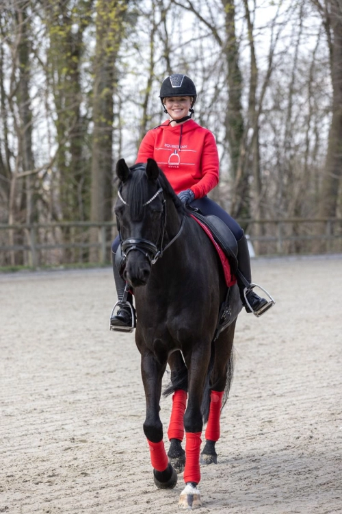 Bluza do jazdy konnej HKM Equine Sports w kolorze czerwonym zaprezentowana przez modelkę podczas jazdy konnej