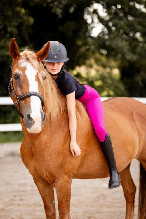 Młodzieżowe legginsy do jazdy konnej Horze Madison w kolorze beetroot pink zaprezentowane przez modelkę podczas jazdy konnej