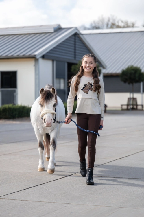Bluzka jeździecka dziecięca HKM Junior Mia w kolorze beżowym zaprezentowana przez modelkę