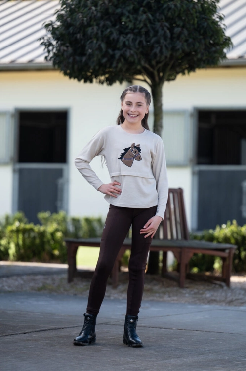 Bluzka jeździecka dziecięca HKM Junior Mia w kolorze beżowym zaprezentowana przez modelkę
