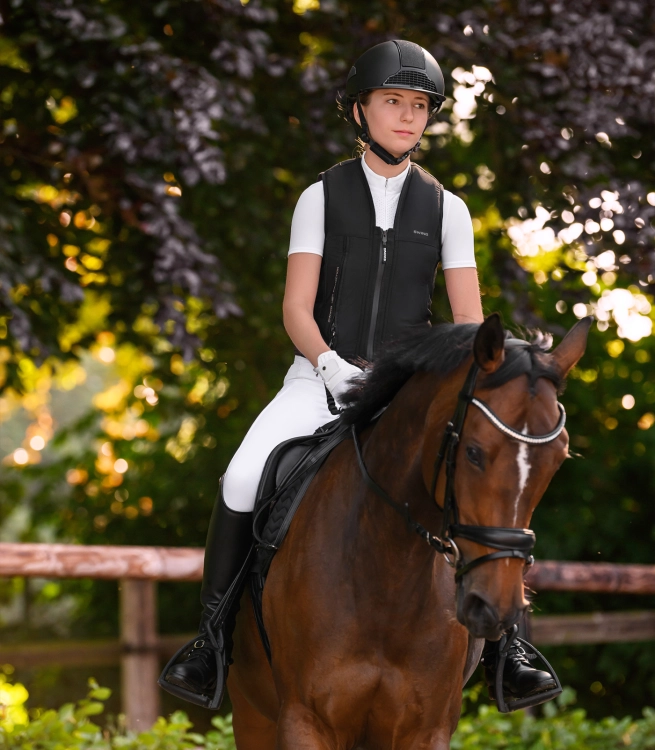 Kask jeździecki Swing H24 Shine w kolorze czarnym zaprezentowany przez modelkę podczas jazdy konnej